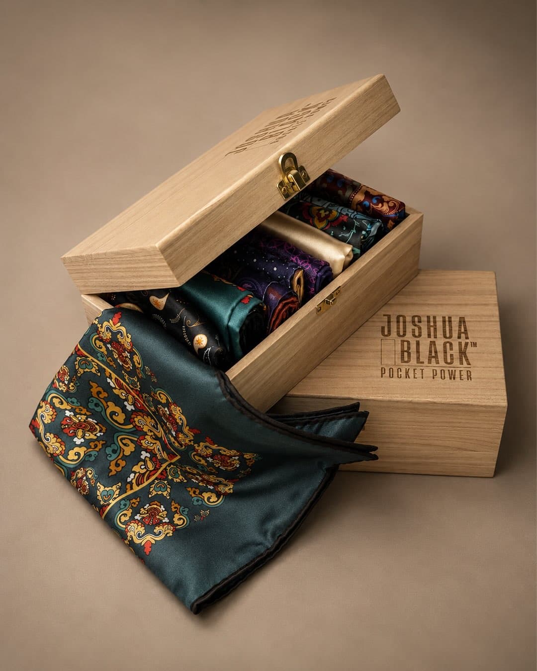 An open wooden Pocket Power box filled with folded pocket squares, an emerald square draped in front